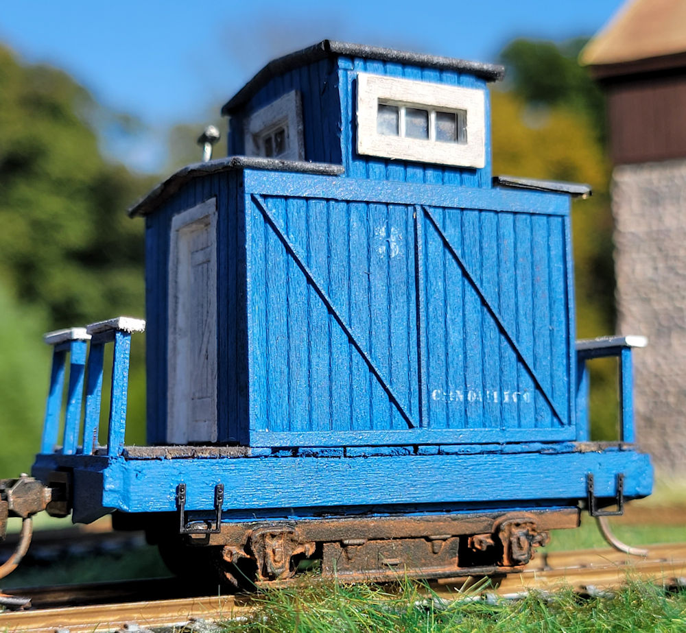 Caboose no. three: A blue caboose against a blue sky and green grass