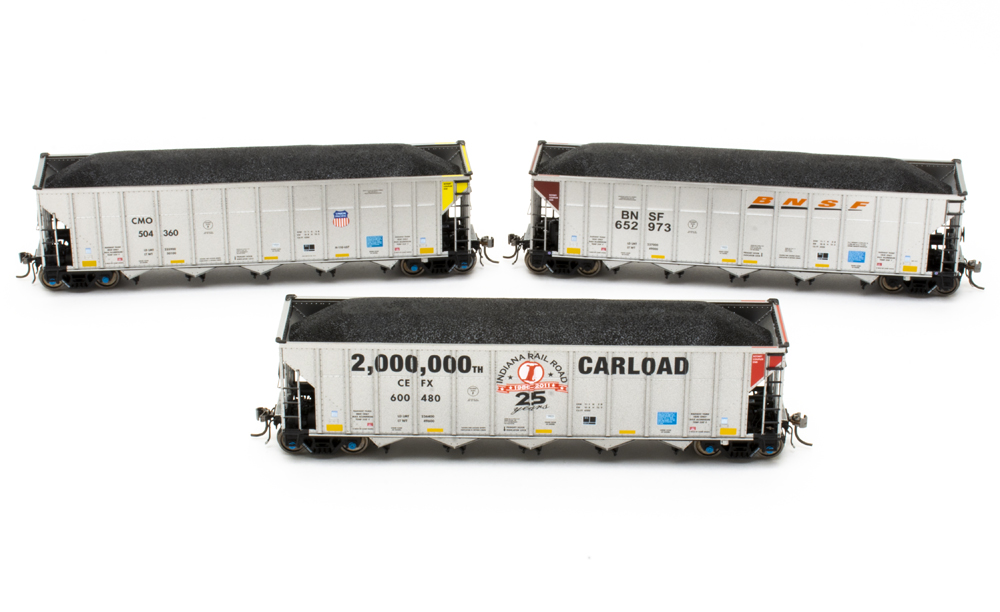 Three gray model hopper cars against a white background