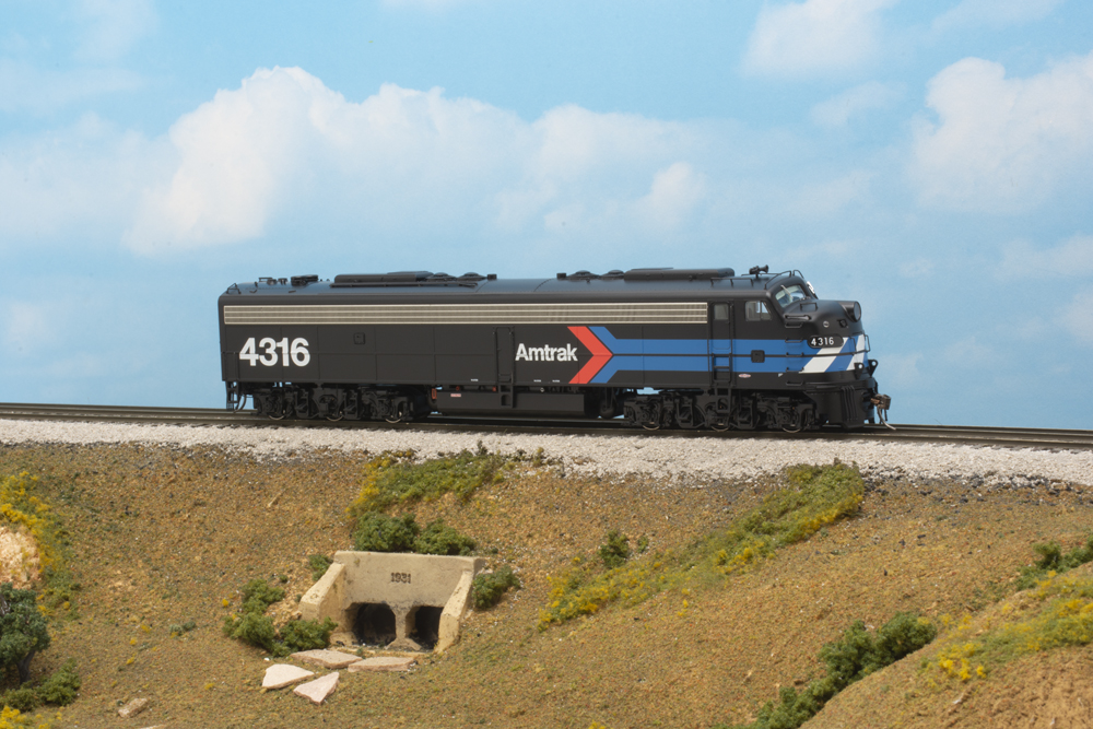 An image of a black model locomotive against a lbue sky background