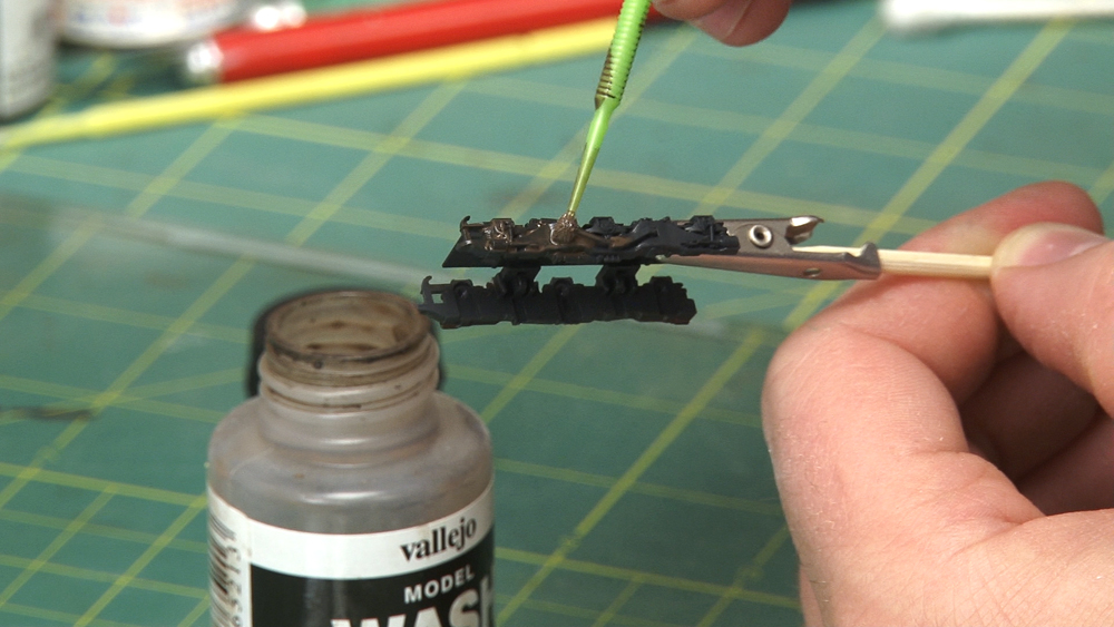A closeup of a model locomotive sideframe as paints are applied.