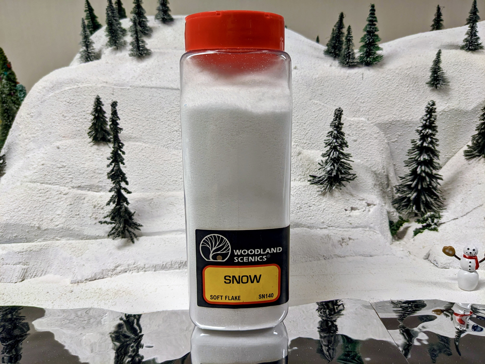 A clear shaker bottle full of white powder with red cap on snowy scenery base