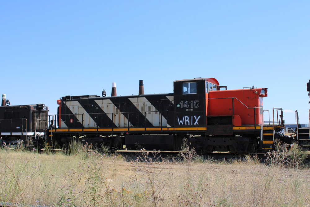 Black white and red switching locomotive in a rail yard.