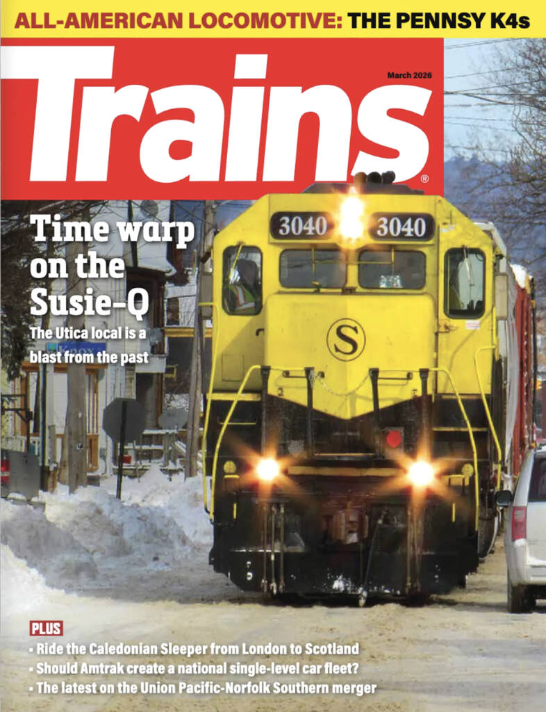 The cover of Trains magazine for March of 2026, which features a yellow locomotive advancing towards the camera in a snowy town