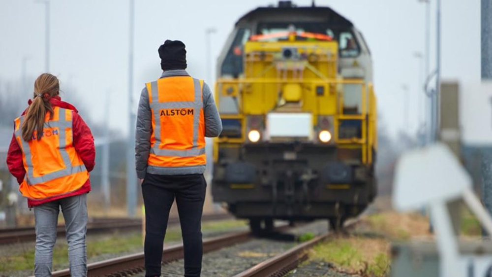 Two people in high visibility vests observing switch engine