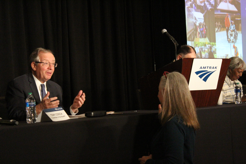 Man seated at podium talking with woman