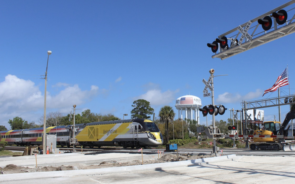 Yellow and white passenger train at grade crossing