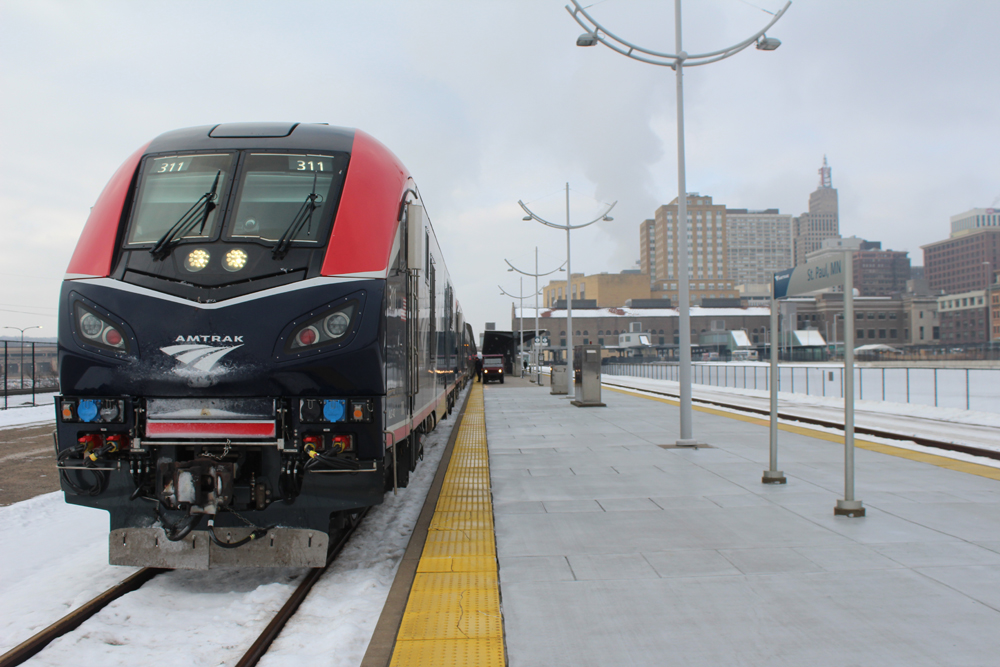 Train at station platform with city skyline in distance