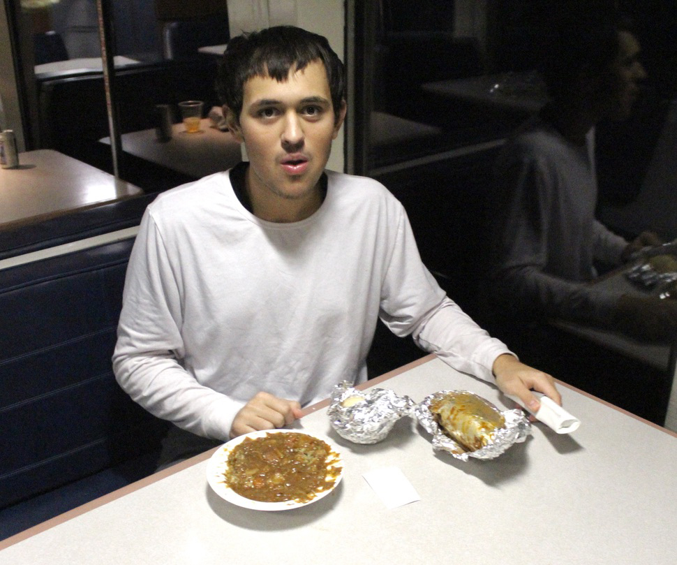 Man in white short at dining table with bowl of food