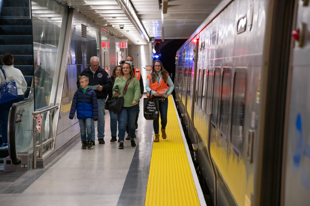 People walk on station platform next to stopped train