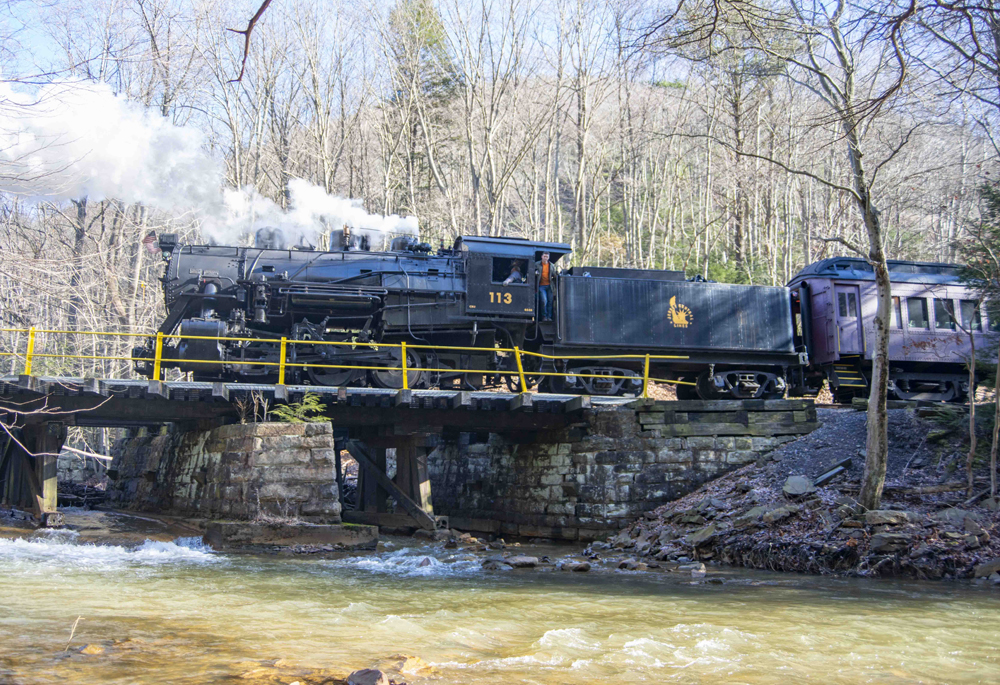 Steam locomotive and passenger train across bridge