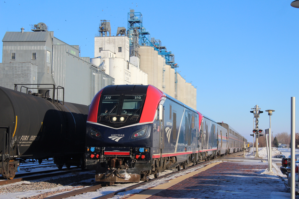 Passenger train with two blue locomotives with red trim