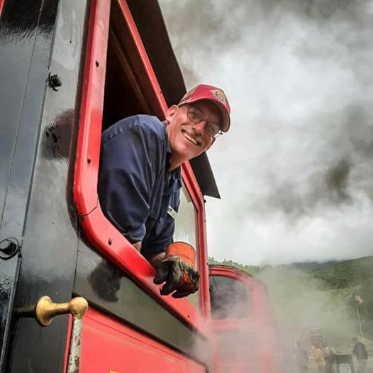 Man leaning out of cab of steam locomotive