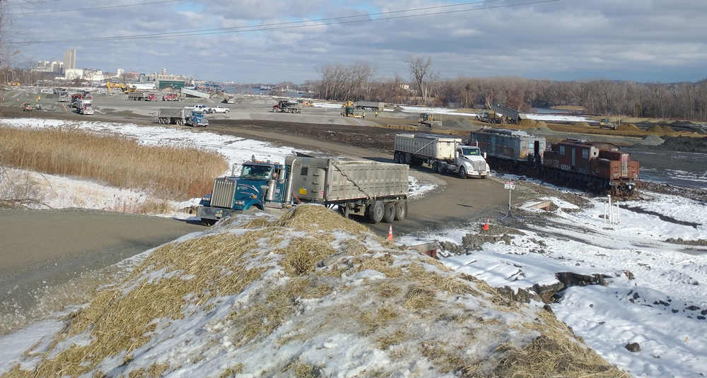 View of roadway with several trucks, with two locomotives sitting off to one side