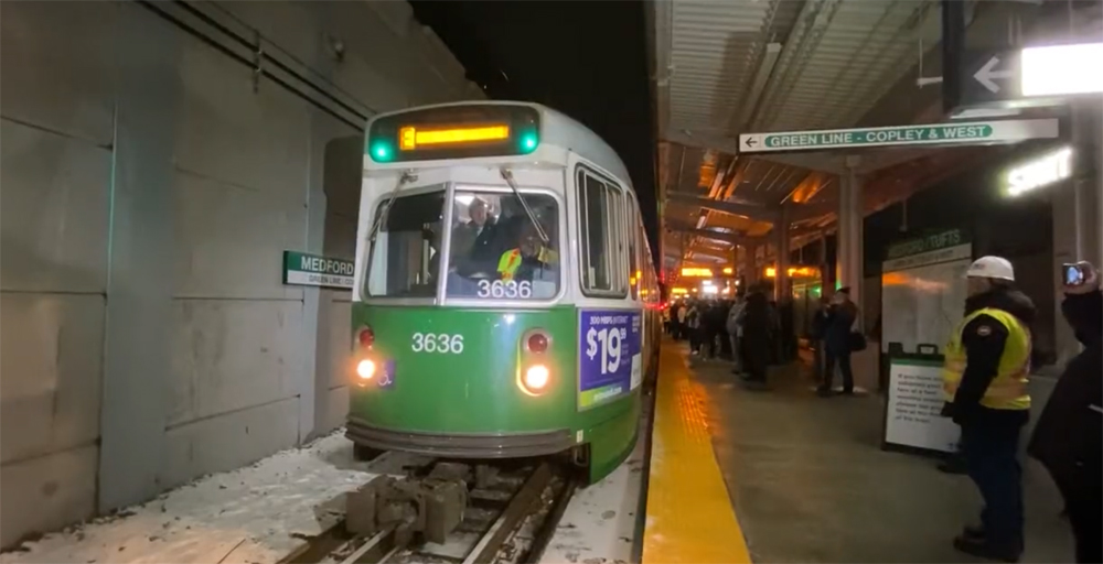 Green and white light rail vehicle at station