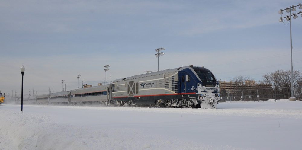 Amtrak Midwest regional train traveling with heavy snow cover on ground