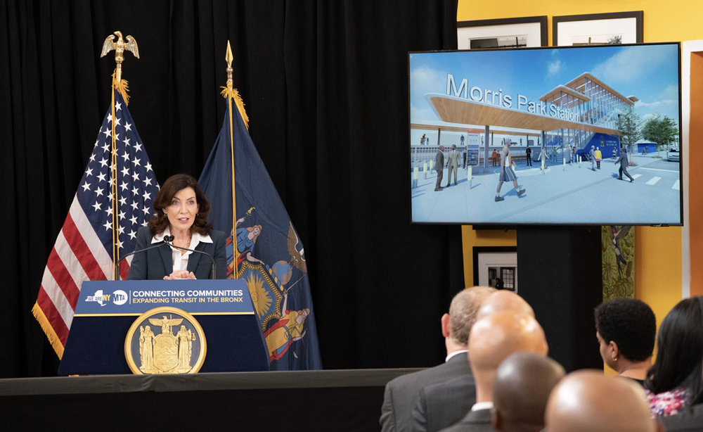 Woman speaking at podium with video screen to her left