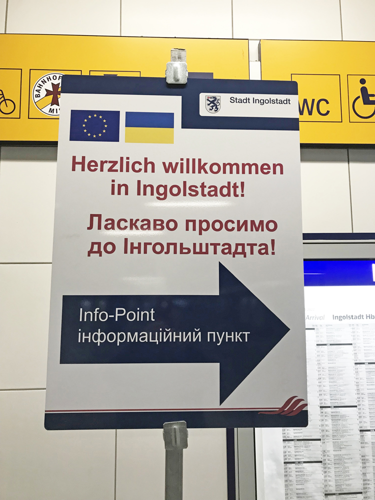 Sign in multiple languages directing Ukrainian refugees to aid location at train station