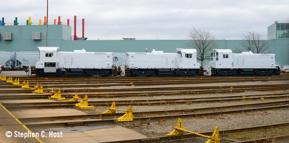 Three white end-cab switchers outside industrial plant