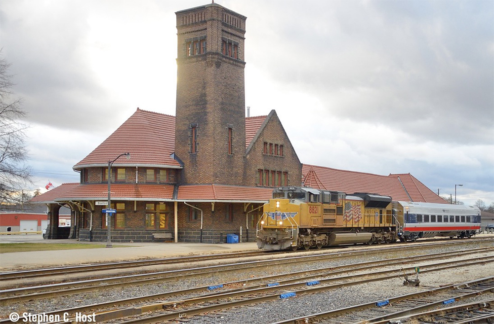 Train passes station with brick tower