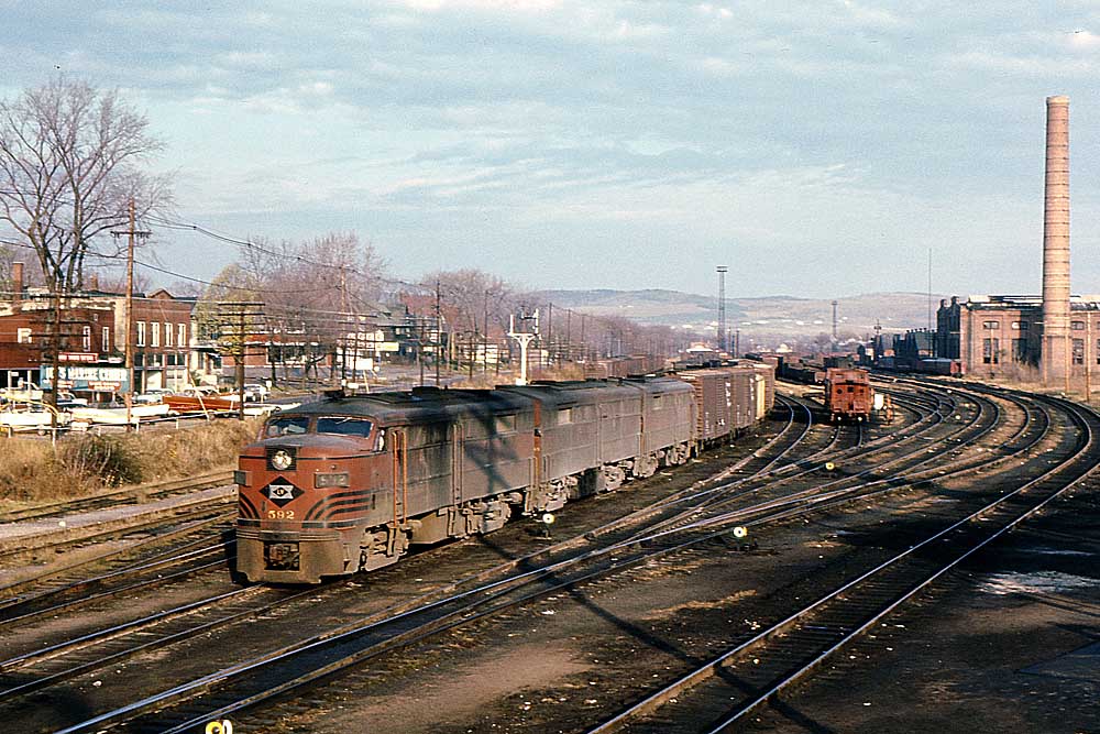 Streamlined red Lehigh Valley Railroad diesel locomotives pull freight train through curve in city
