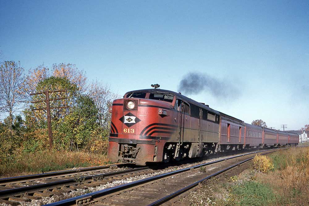 Streamlined red-and-black diesel locomotive on short passenger train on curve