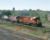 Red-and-yellow and white-and-black on freight train in curve with city skyline