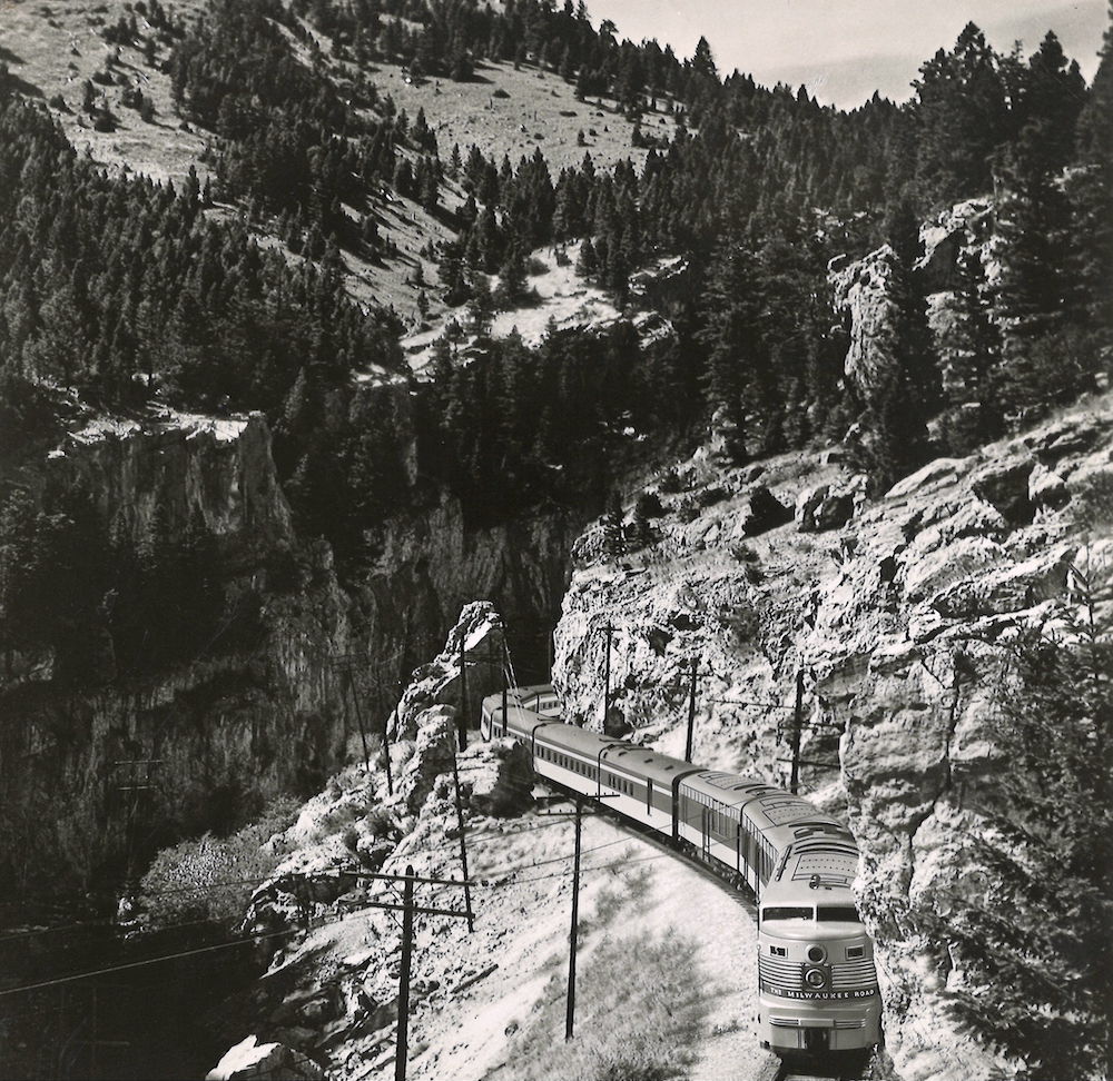 Streamlined passenger train traveling through mountains. 