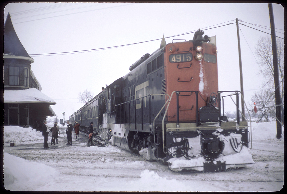 Snow-covered locomotive stopped in front of a station.