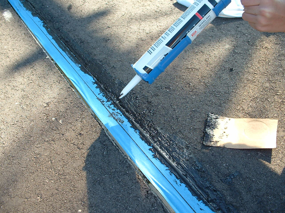 applying driveway sealer to gap in gauge-1 track in groove