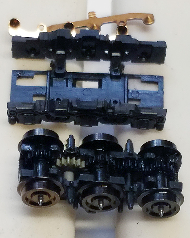 The parts of a disassembled N scale locomotive truck are laid out for cleaning