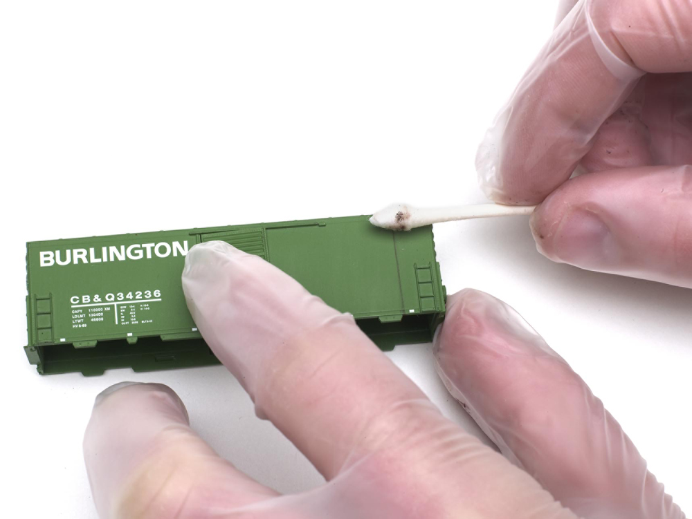 A q tip is used on the side of a green freight car