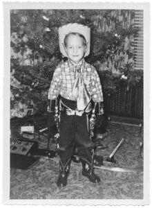 black and white photo of child in cowboy outfit at Christmastime