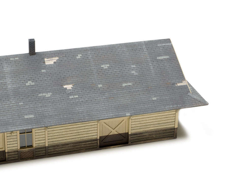 An image of a weathered roof on a model wood structure.