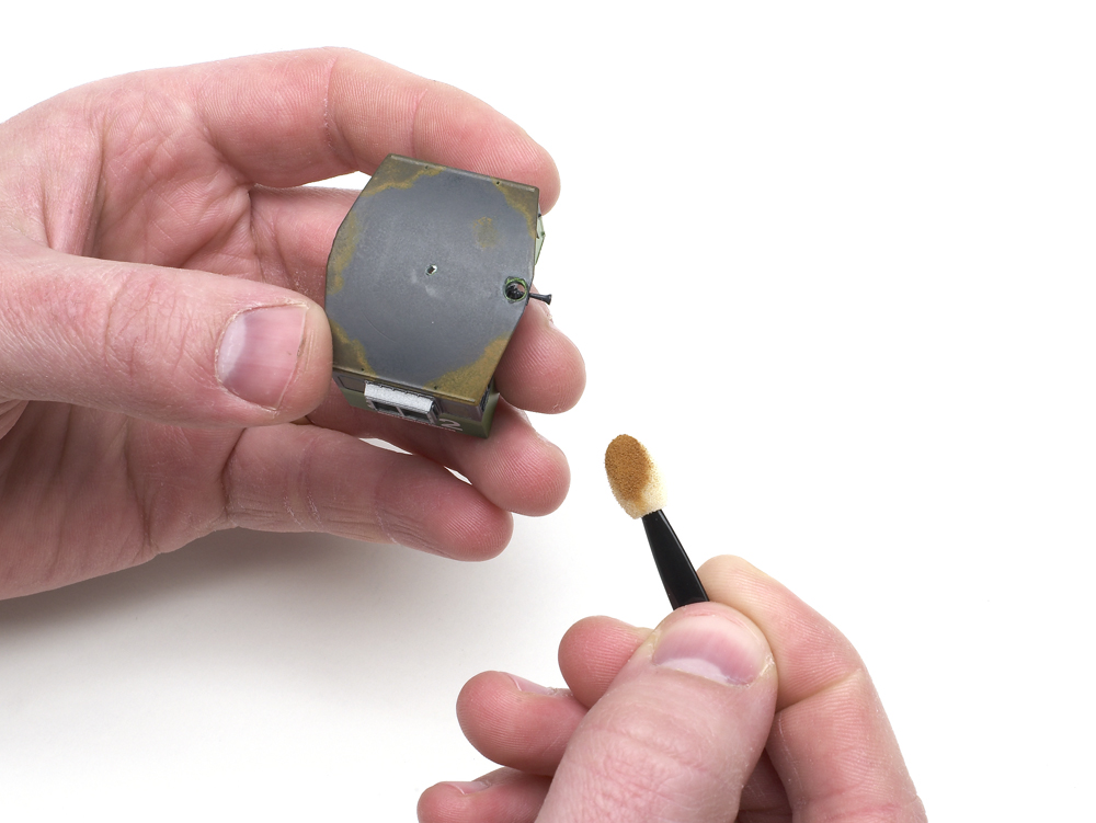 An image of a pair of hands holding a model locomotive and a cosmetic applicator.