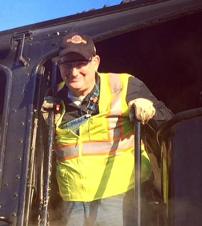 Man in safety vest in door of steam locomotive cab