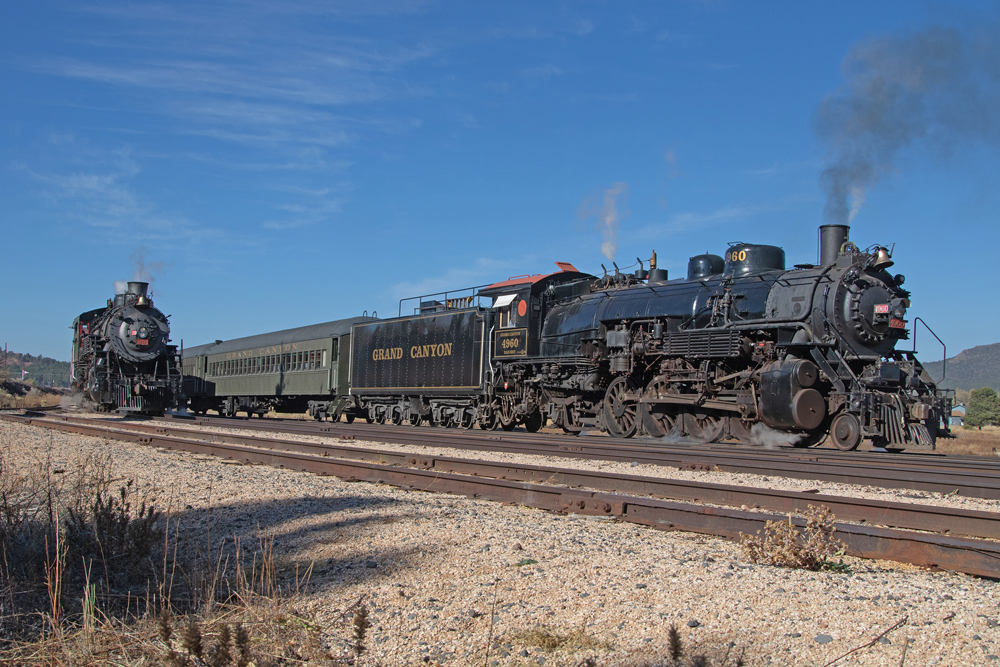 Two steam locomotives pulling passenger trains