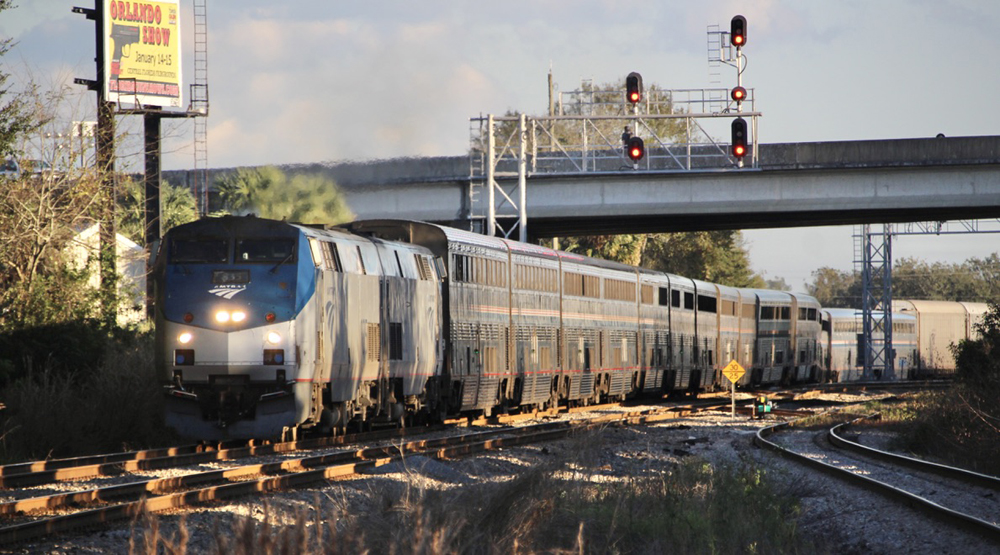 Passenger train with auto racks departs station