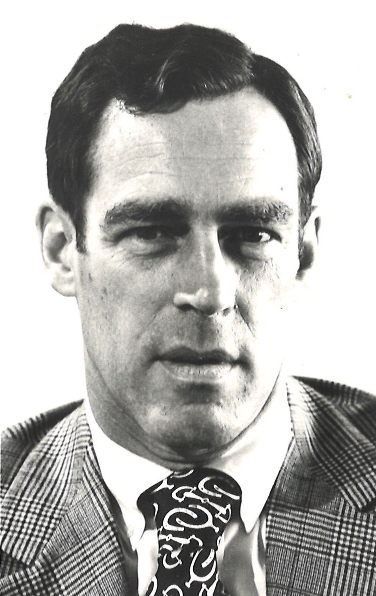 Black and white head shot of man in suit and tie