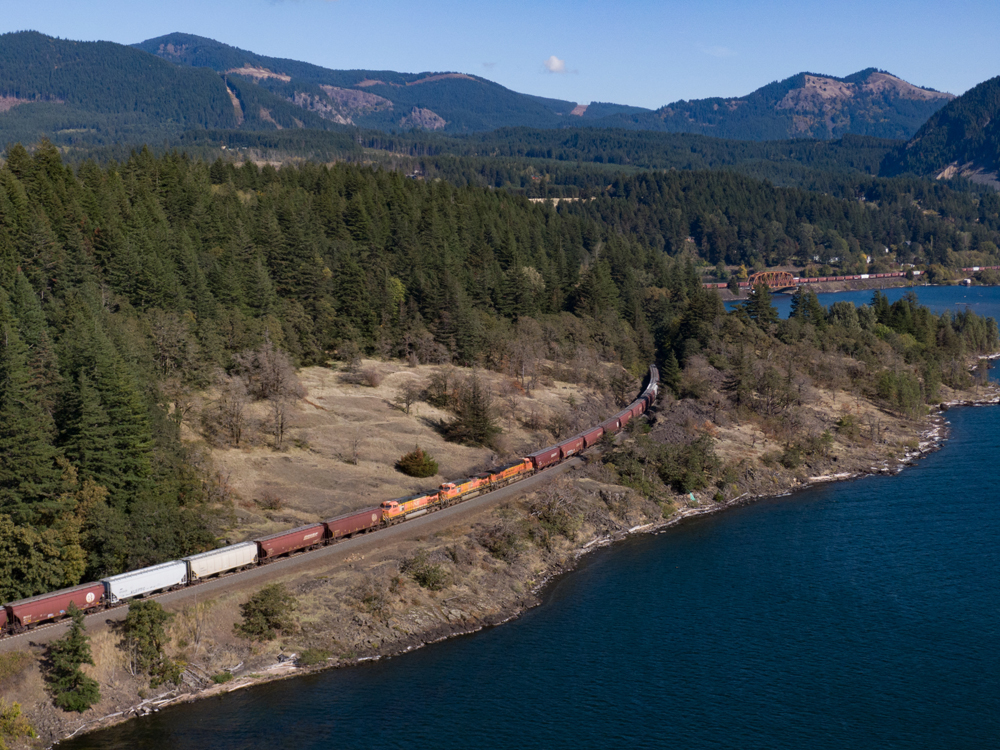Mid-train locomotives in grain train following river