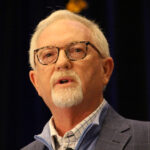 Man with white hair, goatee and glasses