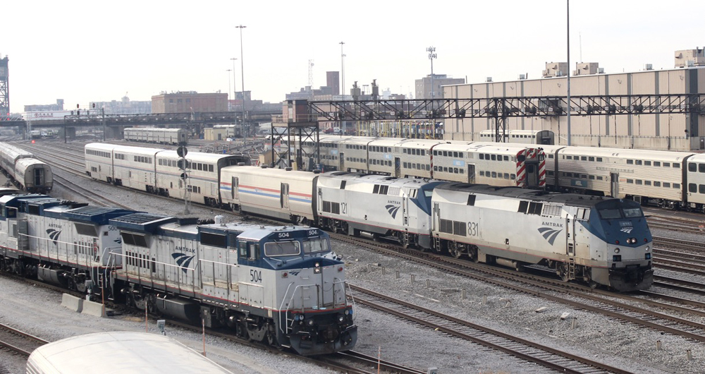 Passenger train with two locomotives and four cars passes through Amtrak yard