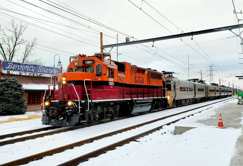 Electric trainset pulled by diesel passes station 