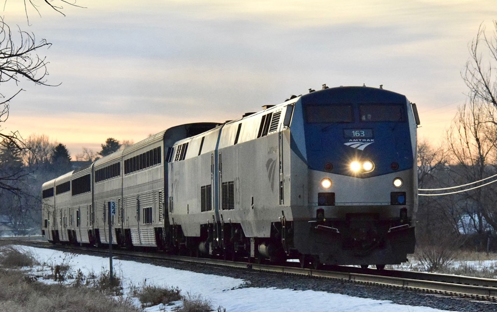 Passenger train with two locomotives and five cars approaches on straight track