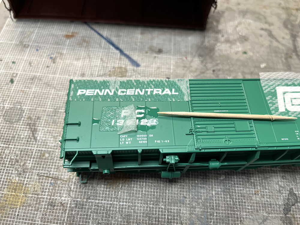 Car Swap Project Part 2: Stripping lettering from models: Green model boxcar with liquid on side and wood toothpick