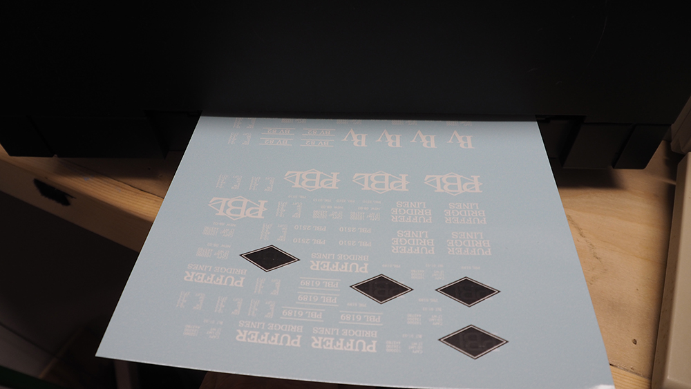 Light blue paper with white letters and black diamonds extending from computer printer