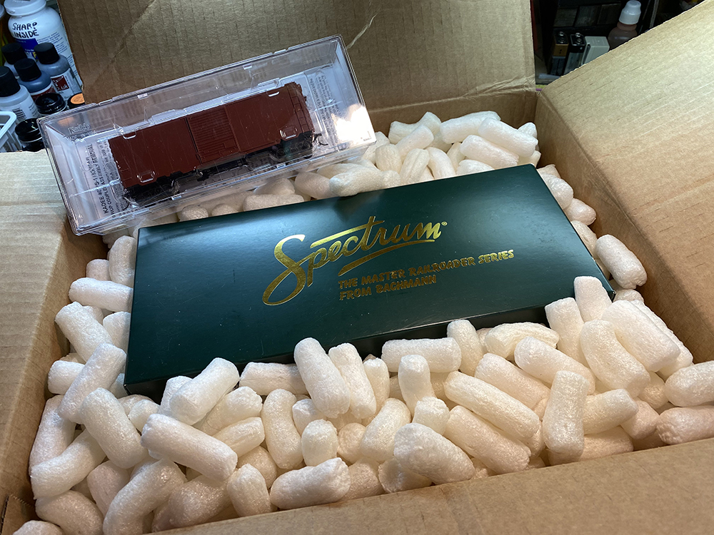 Car Swap Project part 6: Seth’s techniques for decals and weathering: Green box in white packing peanuts with smaller clear box containing a model train car