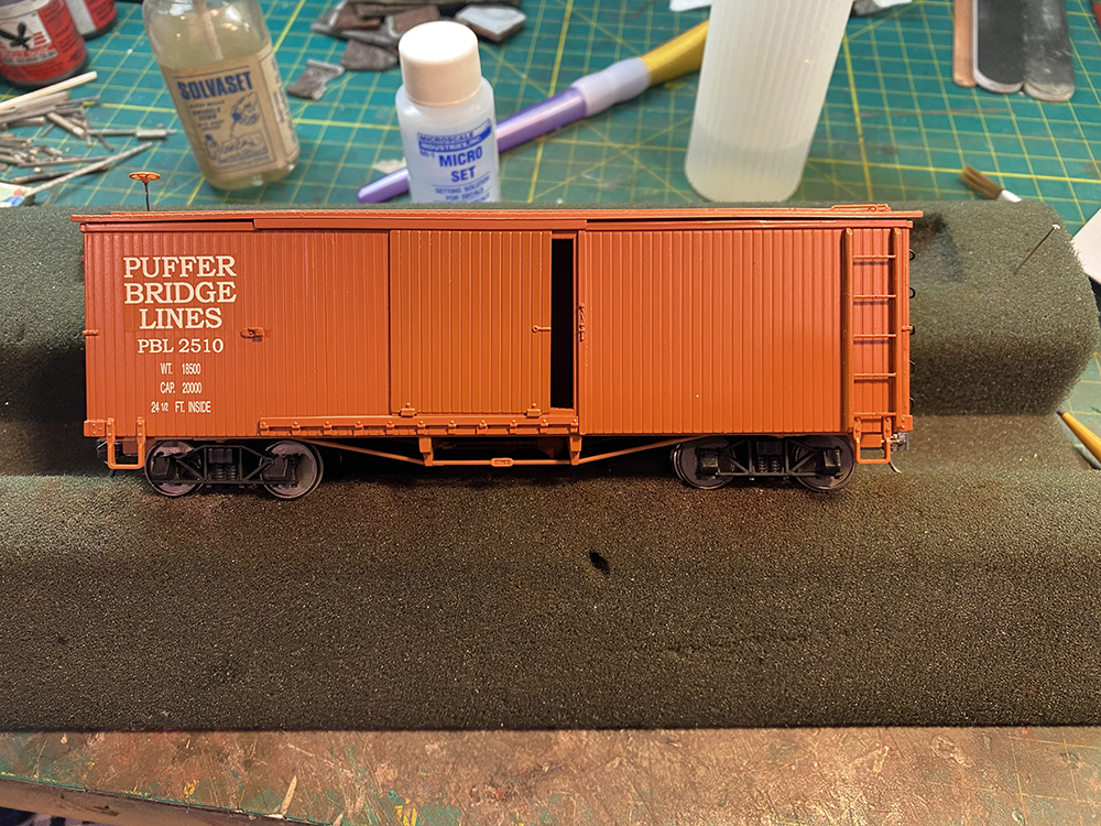 Car Swap Project part 6: Seth’s techniques for decals and weathering: Red model boxcar with white letters sitting on workbench