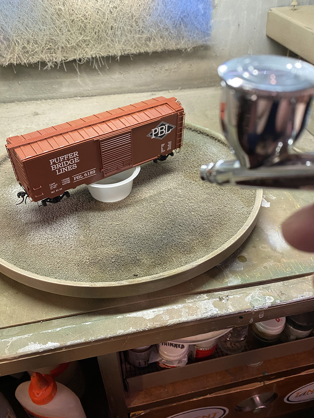 Car Swap Project part 6: Seth’s techniques for decals and weathering: Brown model boxcar in dirty spray booth with sliver airbrush