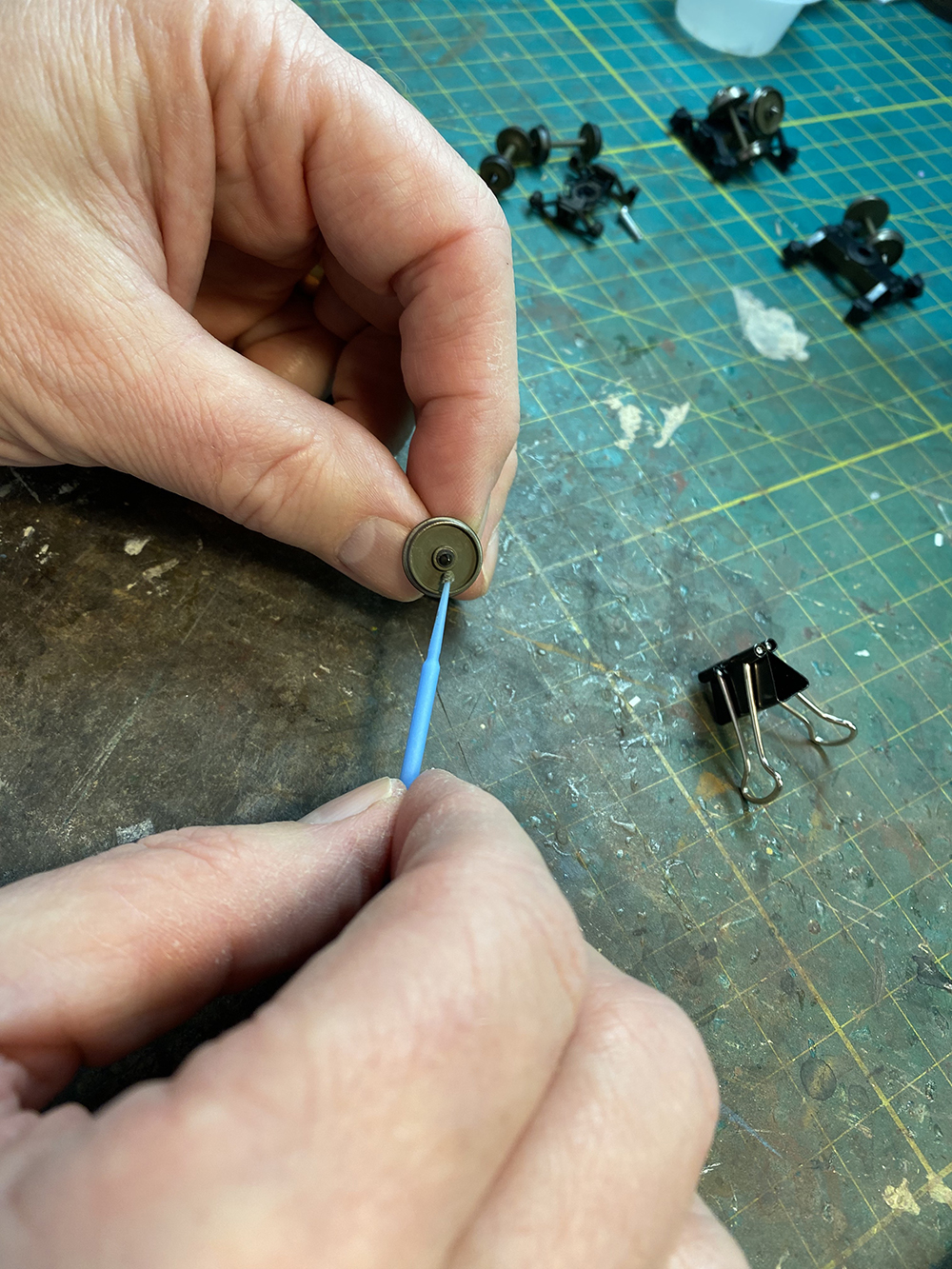 Car Swap Project part 6: Seth’s techniques for decals and weathering: Hand holding small green brush and sliver wheel while painting it brown