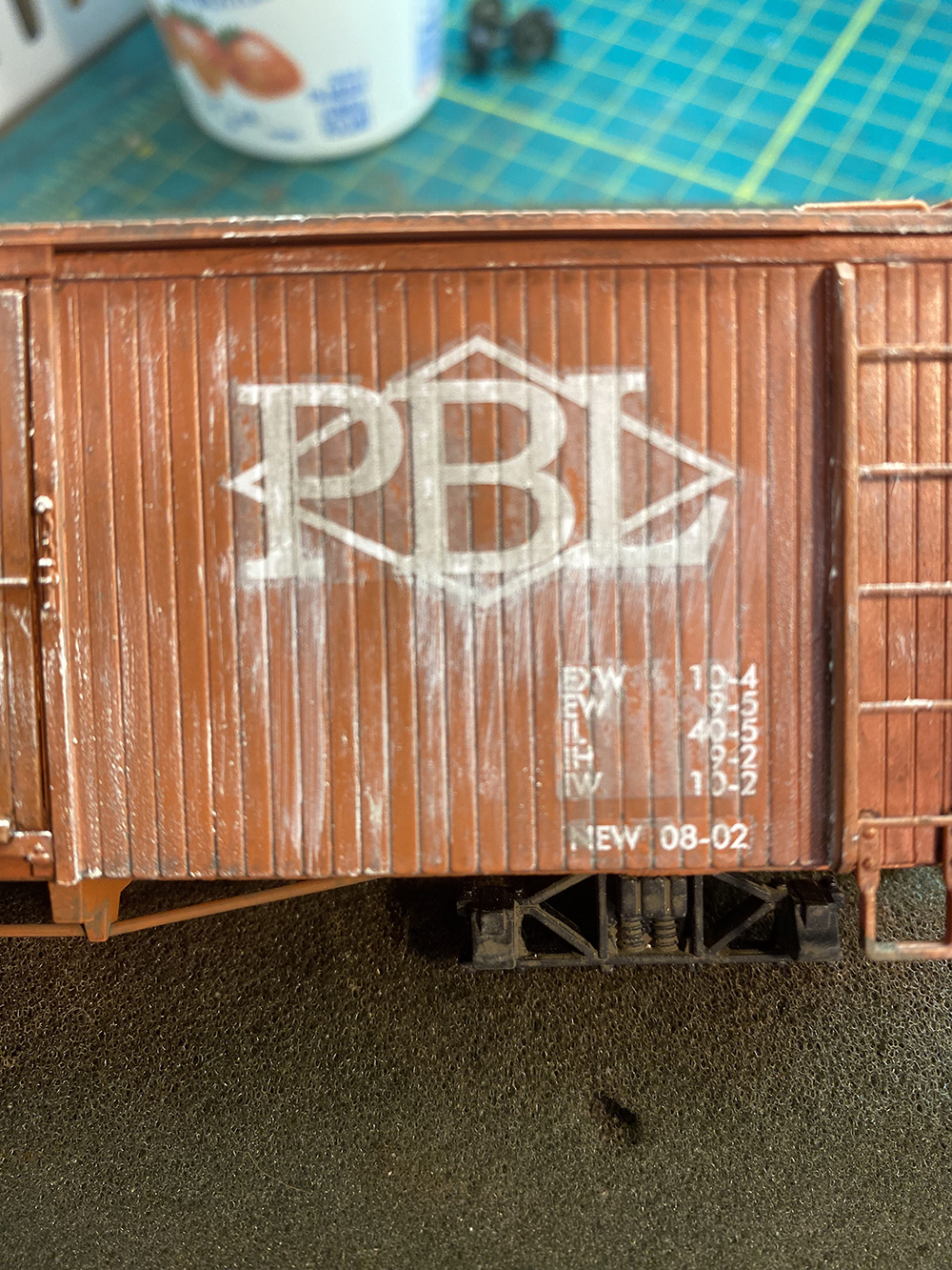 Car Swap Project part 6: Seth’s techniques for decals and weathering: White letters on brown model boxcar with streaked white paint.
